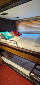 Cozy caravan bedroom with comfortable bedding, pillows, and soft lighting - perfect for a relaxing vacation getaway.