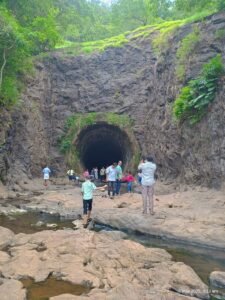 "Tourists standing near the historic Anchuruli Tunnel carved into a forested hillside in Idukki."